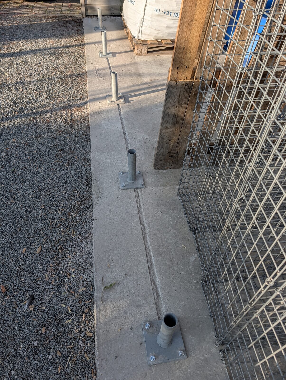Betonstreifen mit verzinkten Fußplatten, auf denen die Stützpfosten verschraubt sind